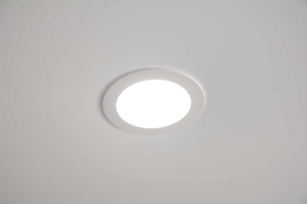 A round, recessed ceiling light is turned on, emitting bright white lighting. The IC rating ensures the fixture is safely installed in the smooth, plain white ceiling. | High 5 Plumbing, Heating & Cooling