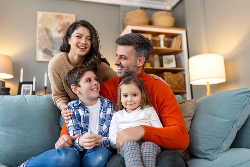 parents and little children sit on sofa together