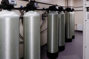 Water softener tanks with control valves installed in a treatment room.